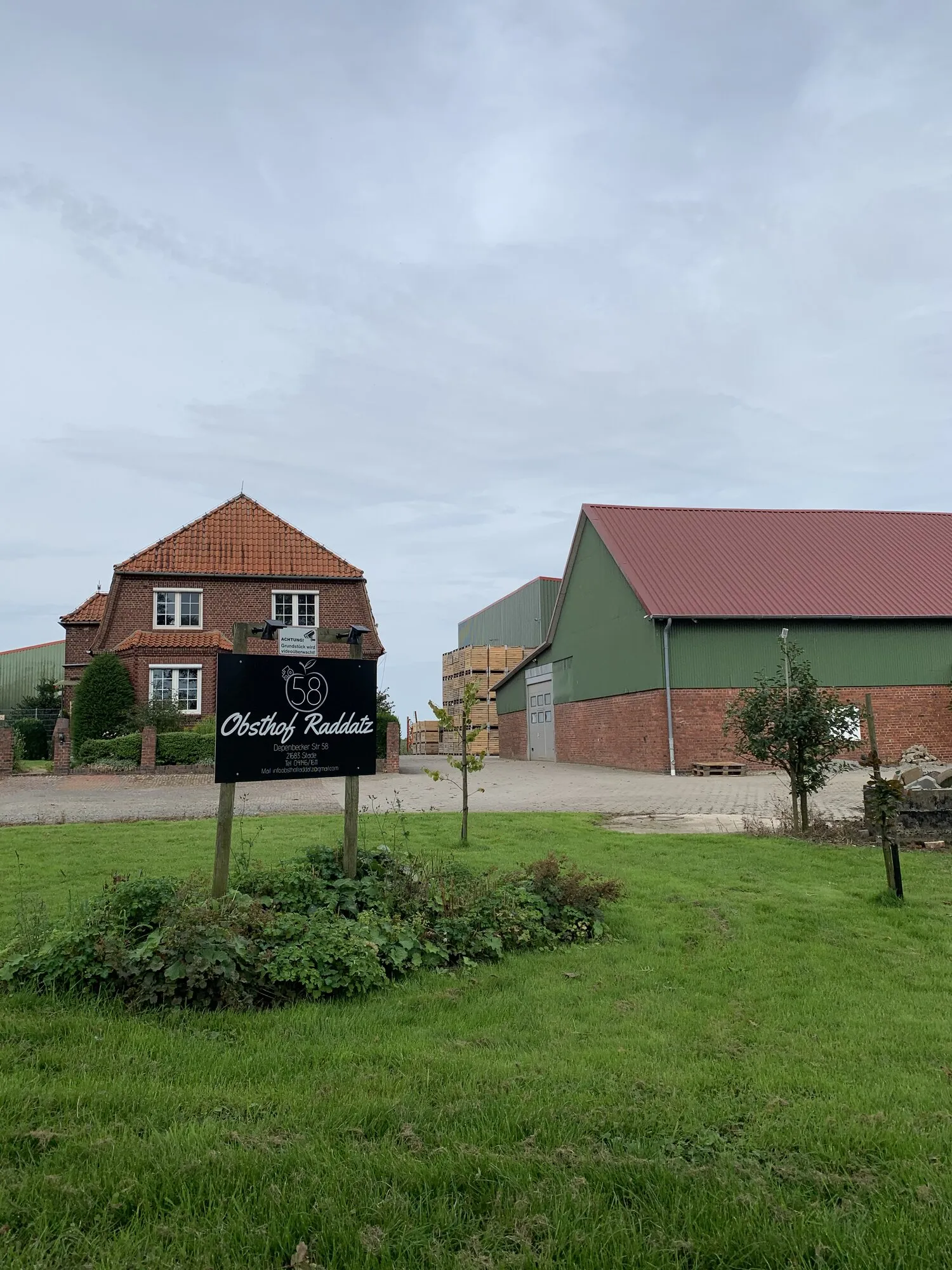 Entrance to Obsthof Raddatz in Stade, Germany, showing the farm sign in front of the traditional brick farmhouse and barns